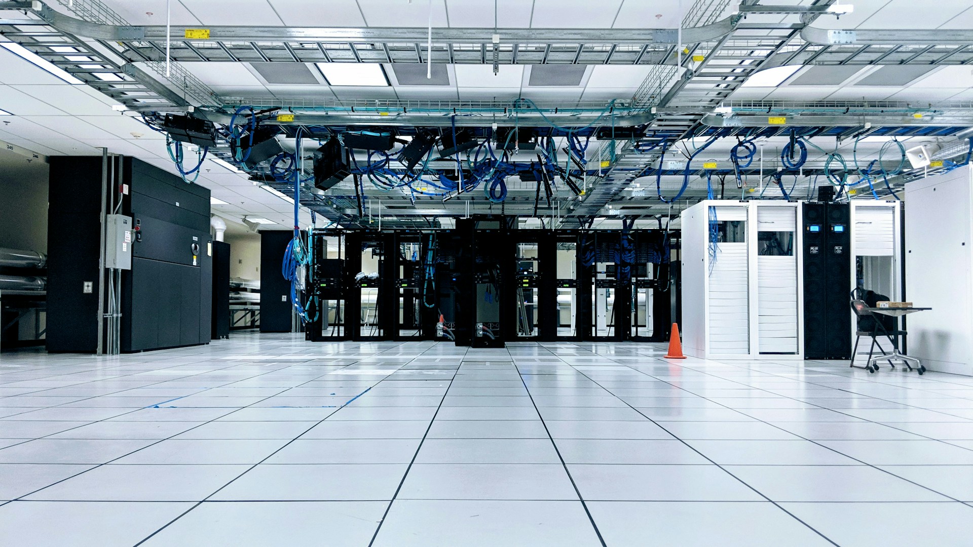 A wide data center floor with server cabinets and overhead cable trays.