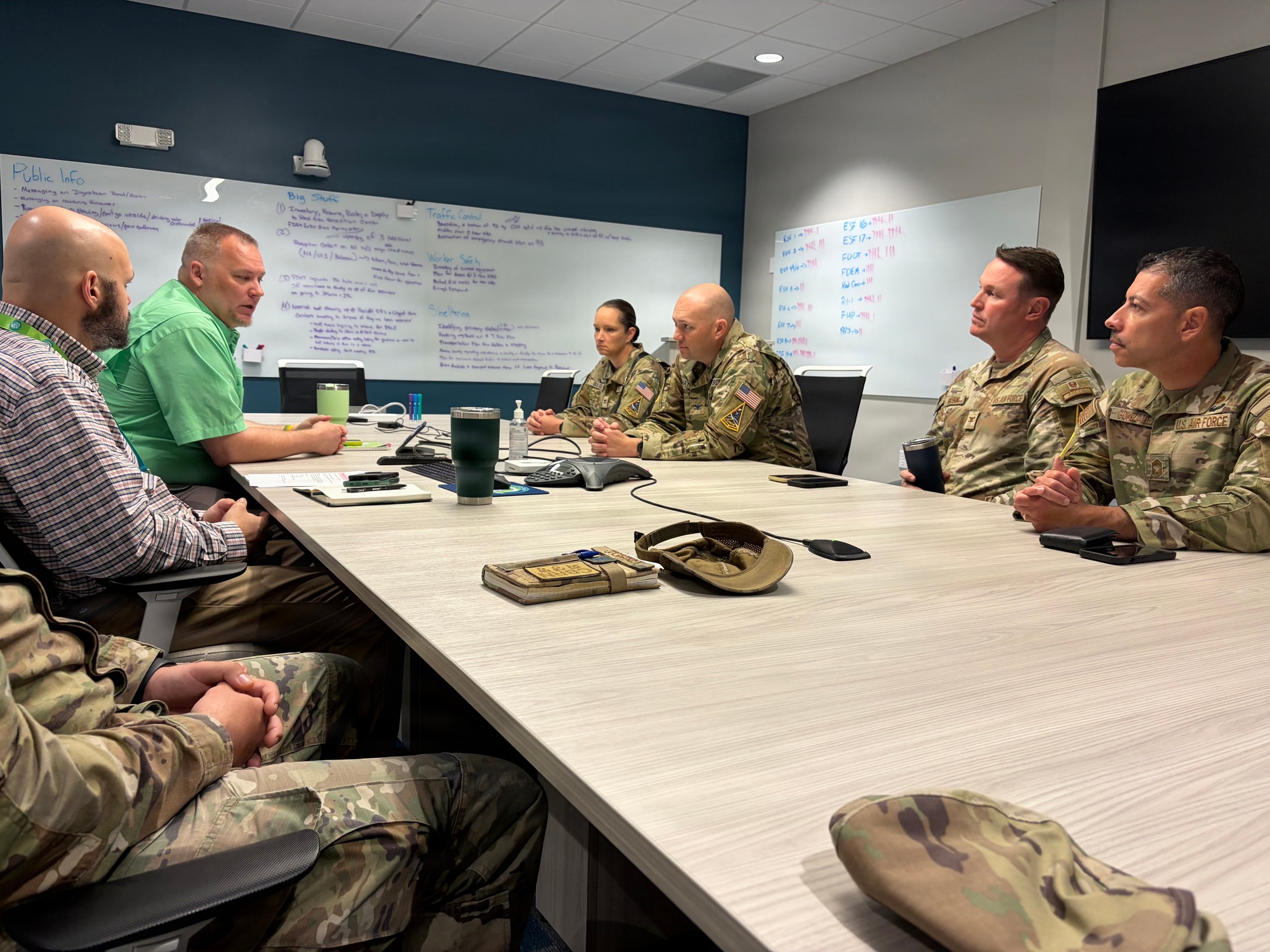Civilian emergency operations staff and Space Launch Delta 45 personnel discuss procedures around a conference table.